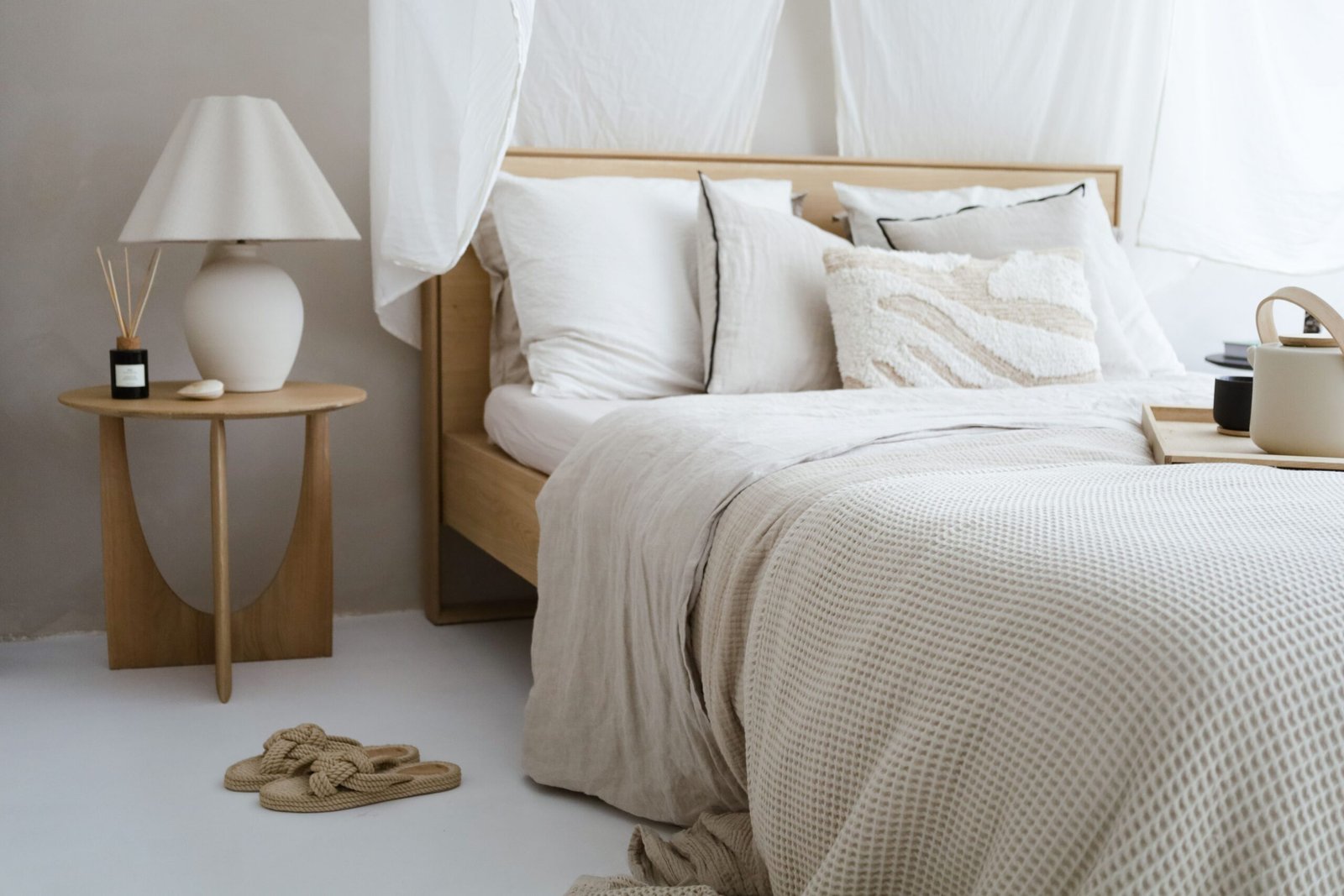 Narrow bedside table next to neutral bed